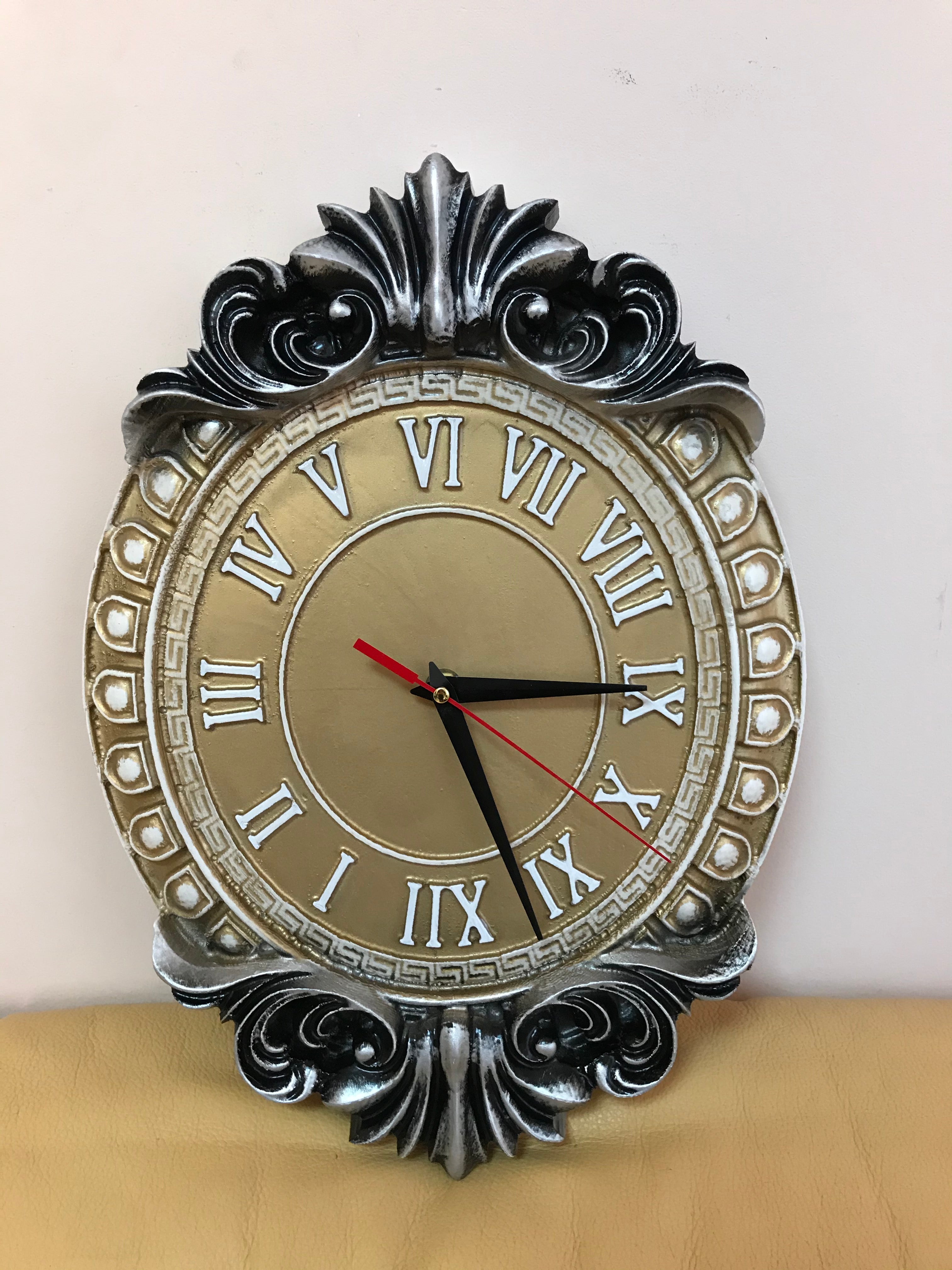 Classic baroque wall clock with Roman numerals in silver and gold tones, decorative oval wooden wall clock