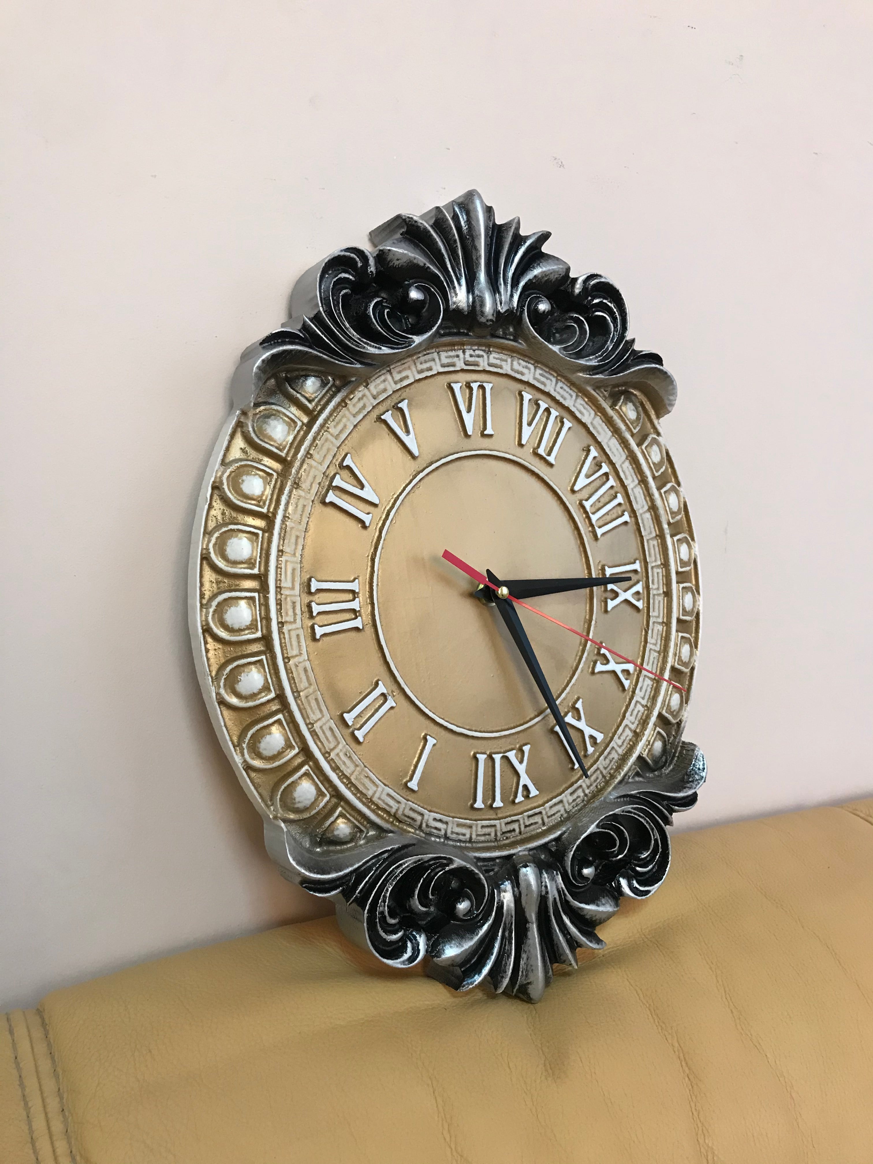 Baroque style wall clock with Roman numerals shown at angle, silver and gold decorative wooden clock