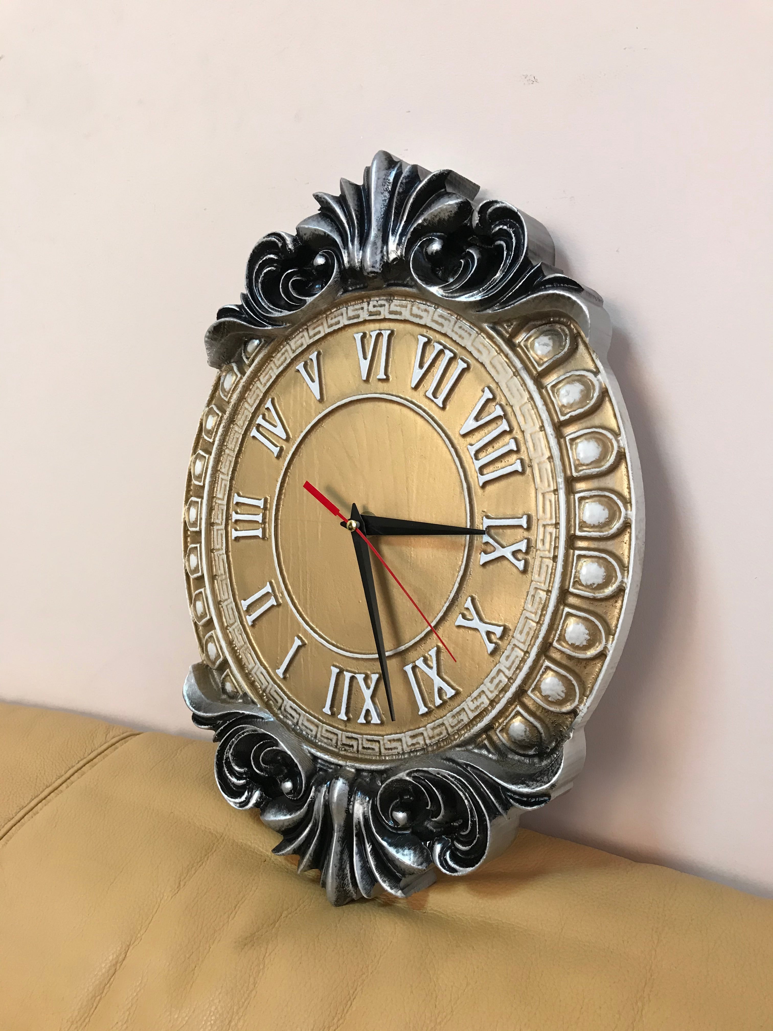 Decorative baroque wall clock in silver and gold finish, oval classic wall decor with Roman numerals