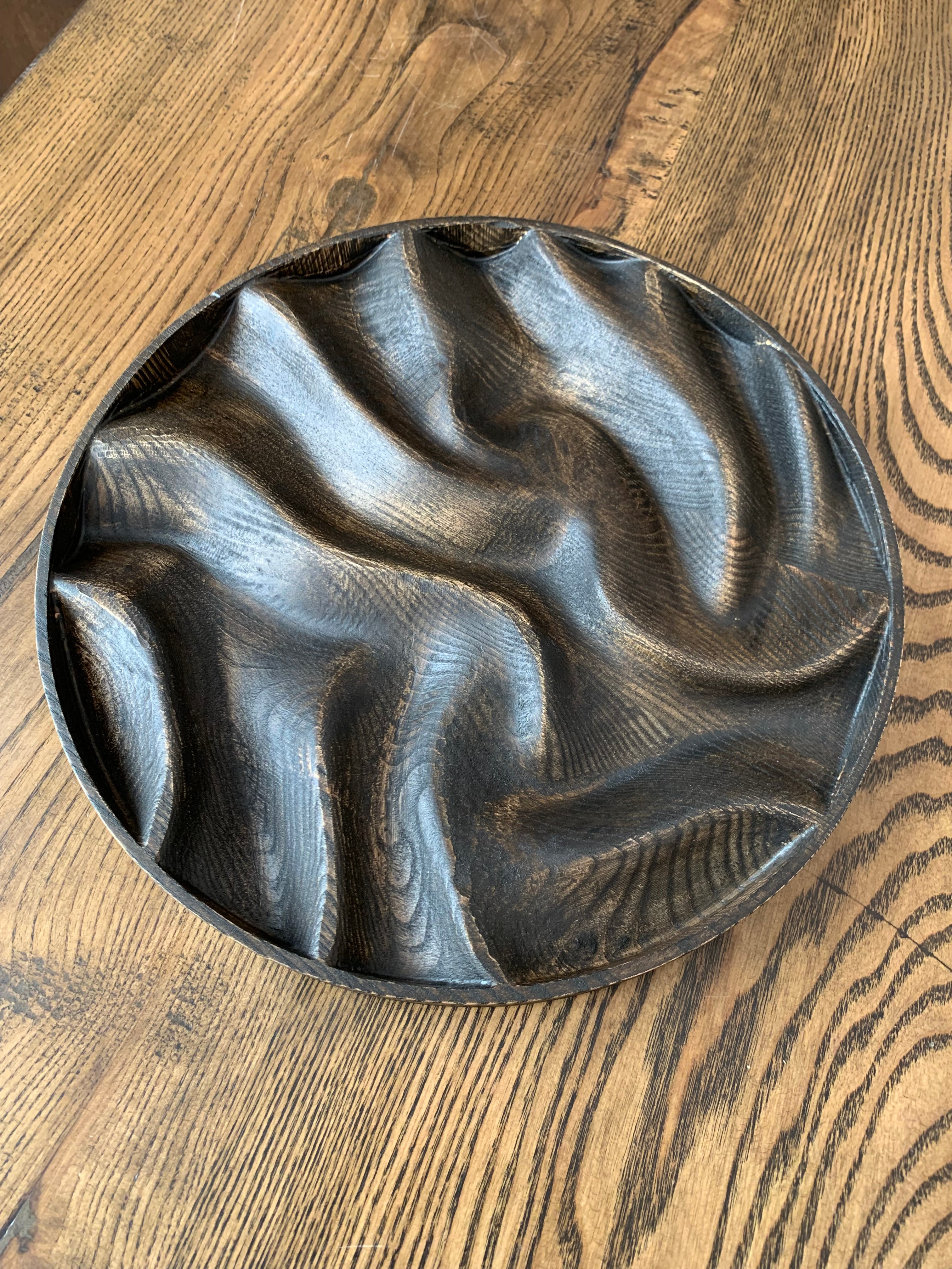 Handcrafted dark ash wood serving platter with organic carved surface, round wooden tray