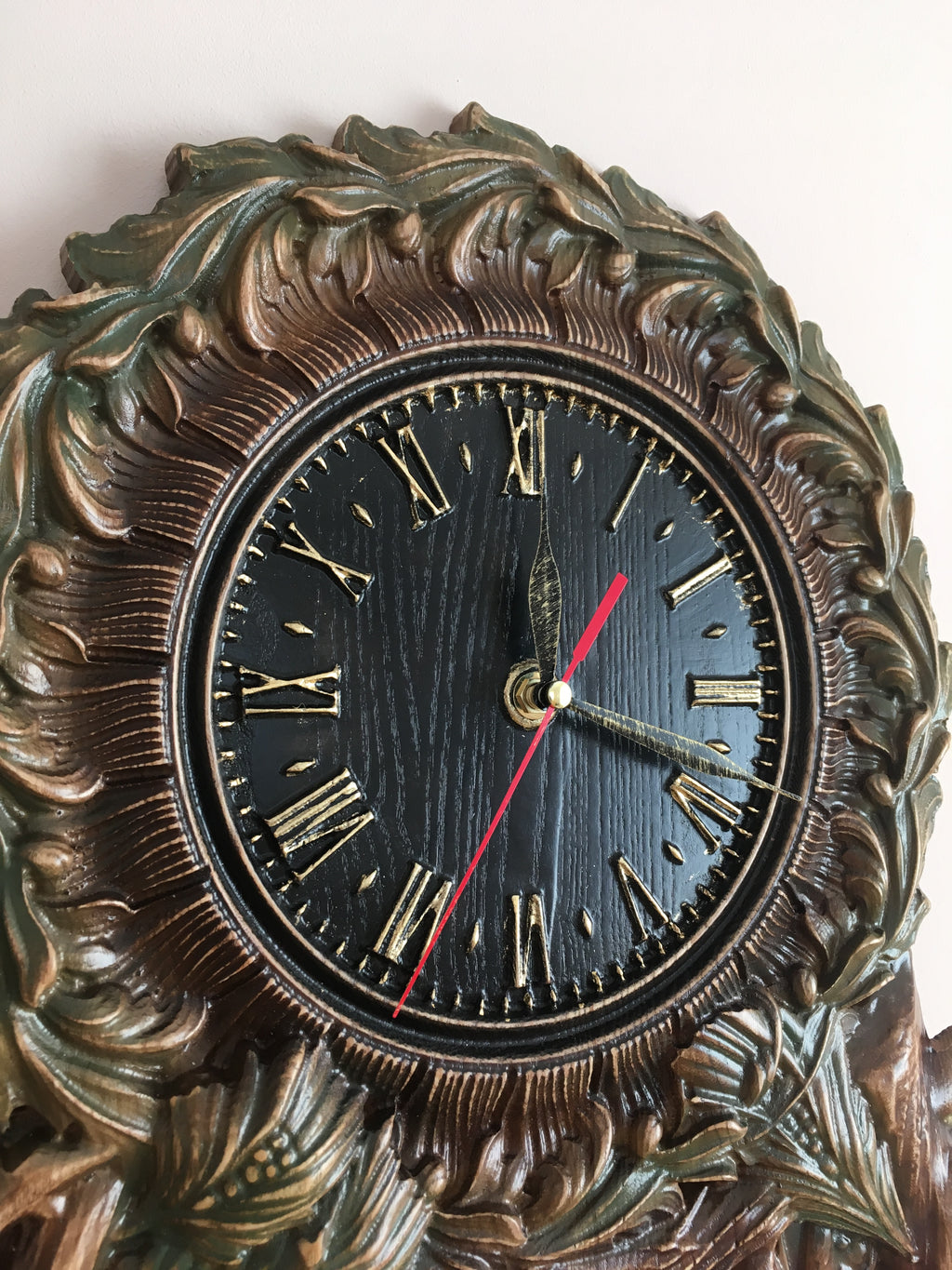 Wooden wall clock with black dial and Roman numerals, carved ash wood frame