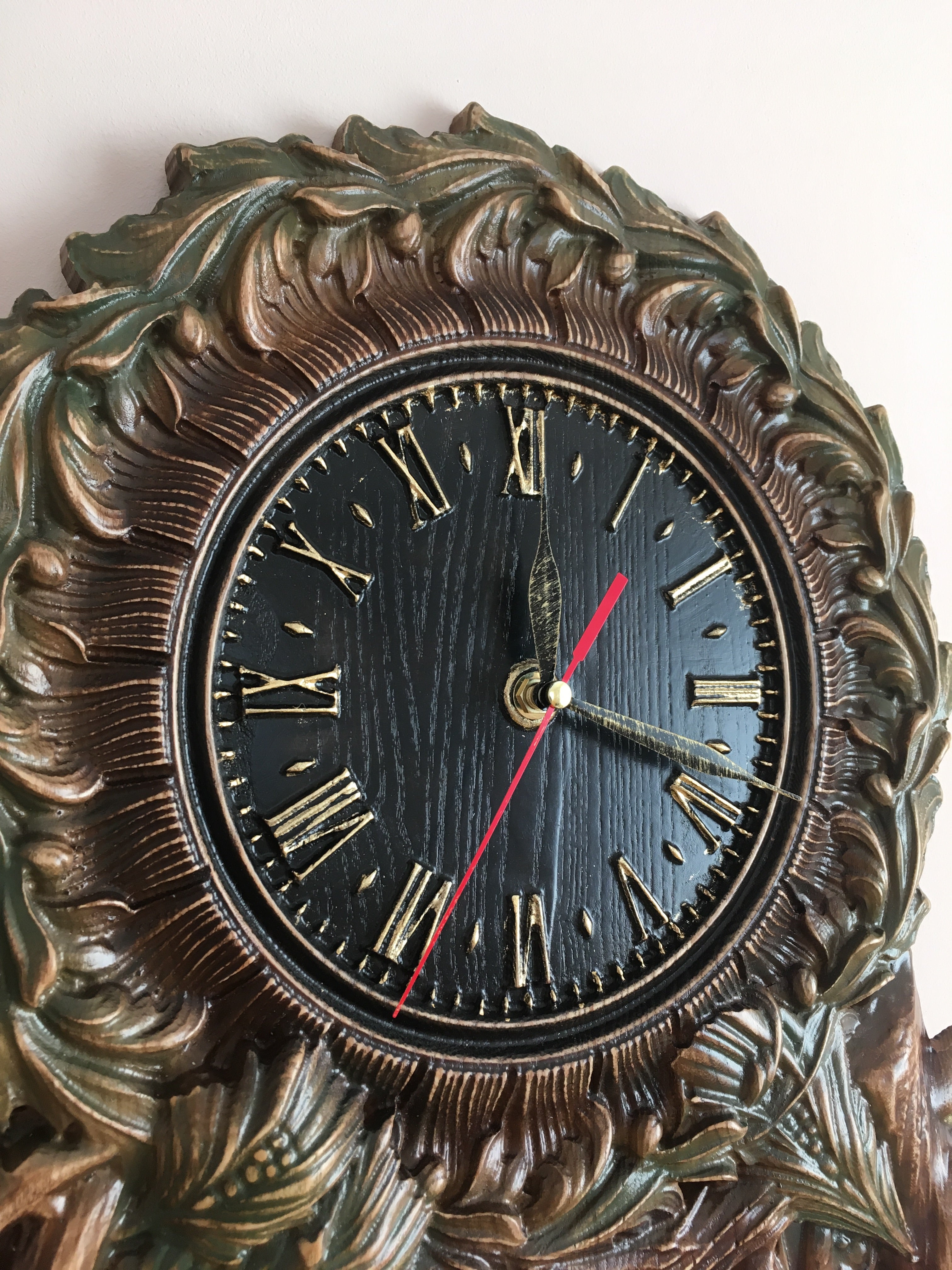 Wooden wall clock with black dial and Roman numerals, carved ash wood frame
