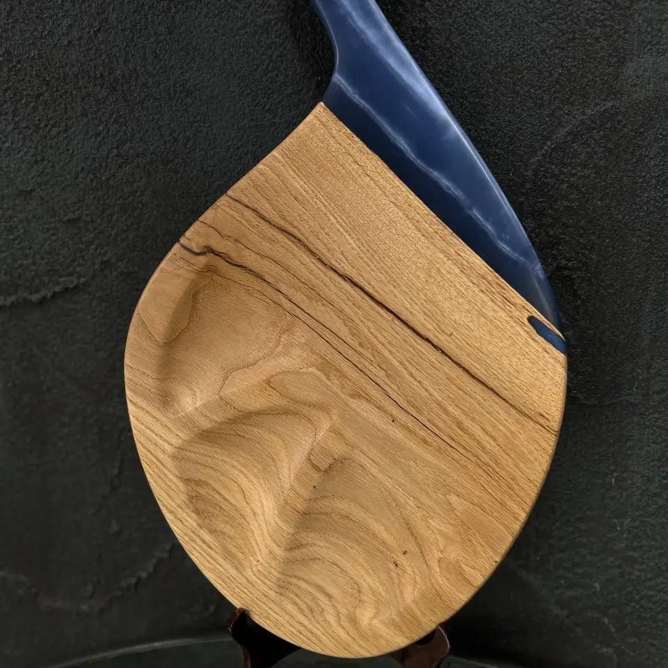 Teardrop-shaped wooden charcuterie board with natural wood grain and blue resin