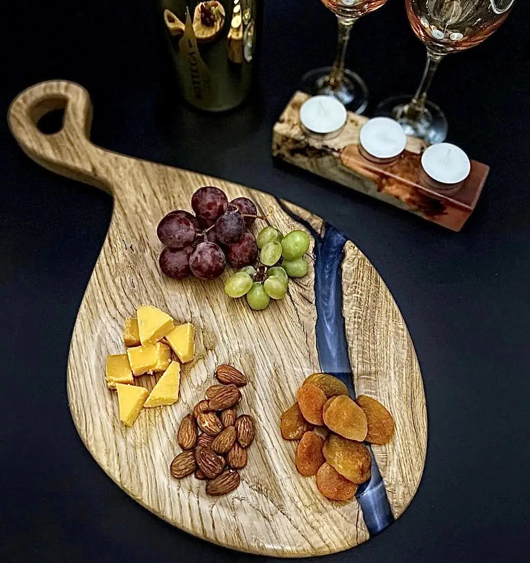 Handmade oak wooden serving board with blue epoxy resin and ergonomic handle.