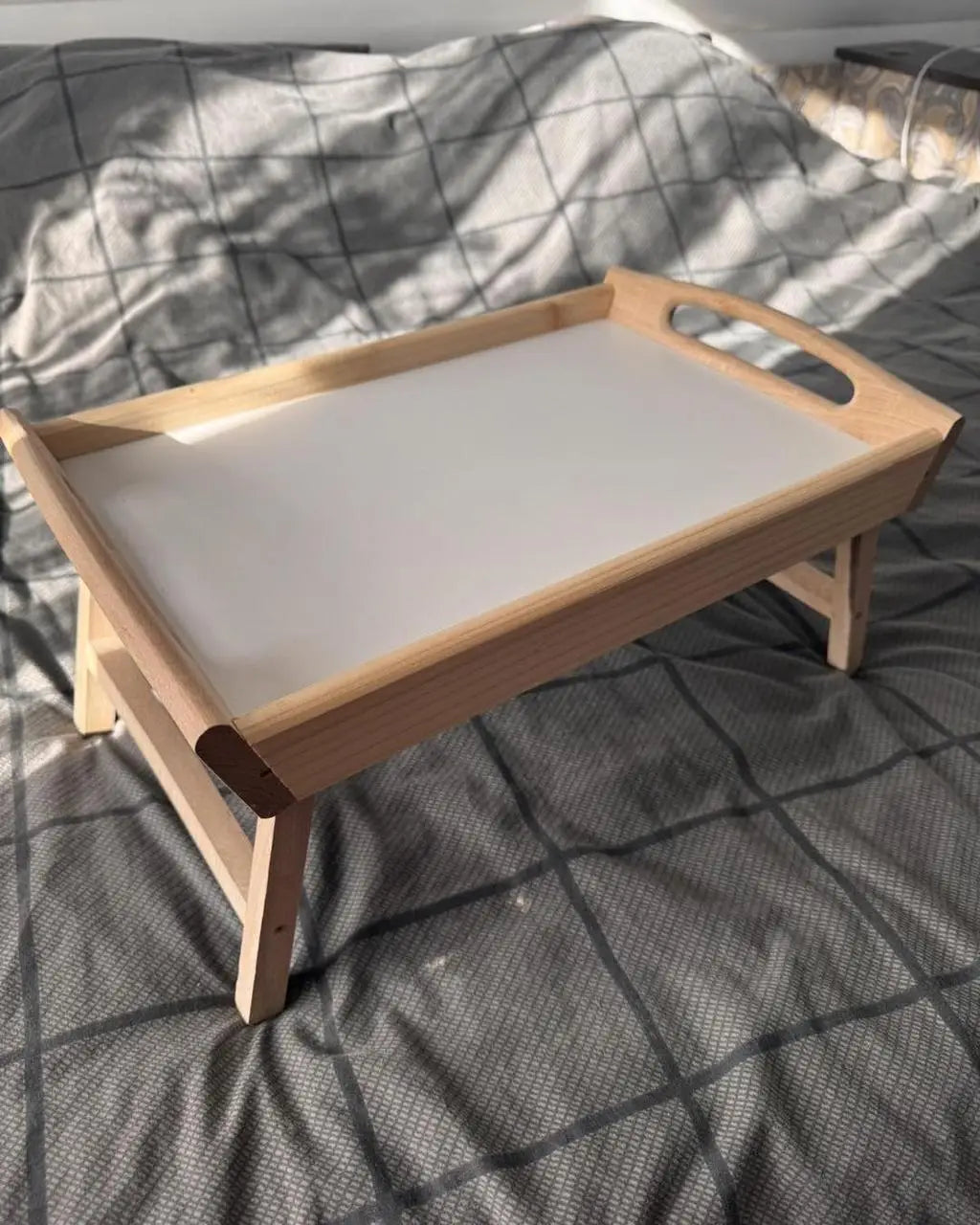 Wooden breakfast-in-bed table with white base on bed