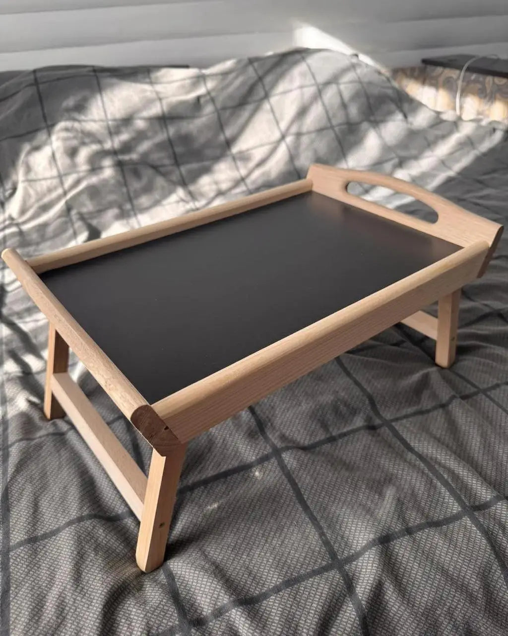 Wooden breakfast in bed tray with black base on bed
