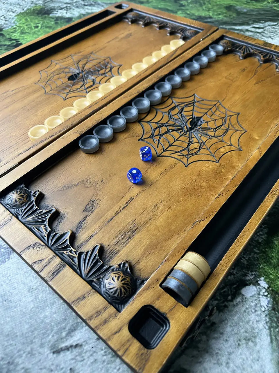 Open wooden backgammon board featuring carved spider artwork