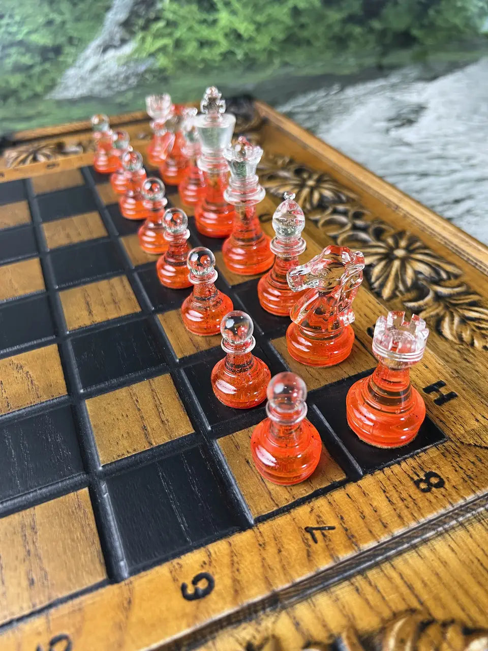 Red crystal chess pieces made of epoxy resin on wooden chess board