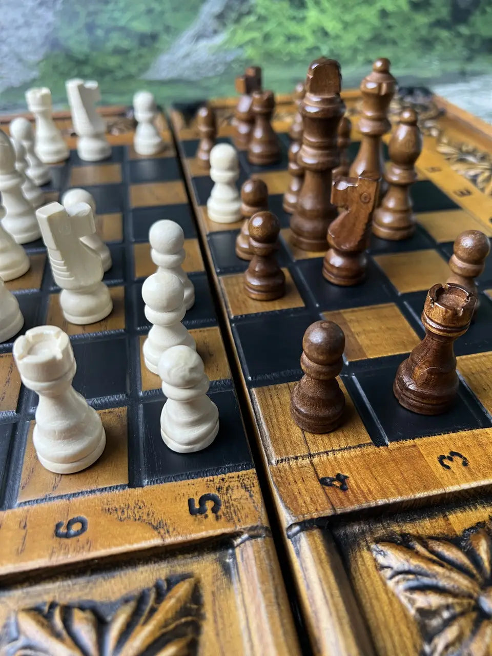 Handcrafted wooden chess pieces on carved wooden chessboard, close-up game setup