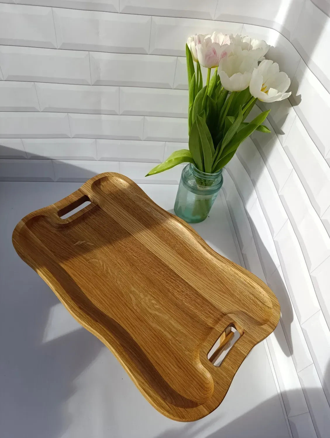 Top-down view of a handmade wave-shaped tray table with carved handles and a natural finish.