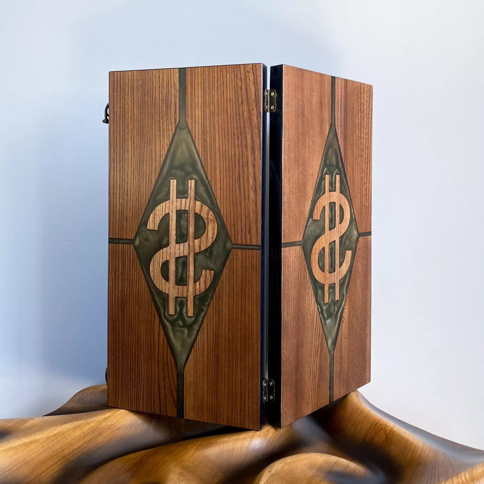 Closed wooden backgammon board with carved dollar symbol and green resin diamond on the front.