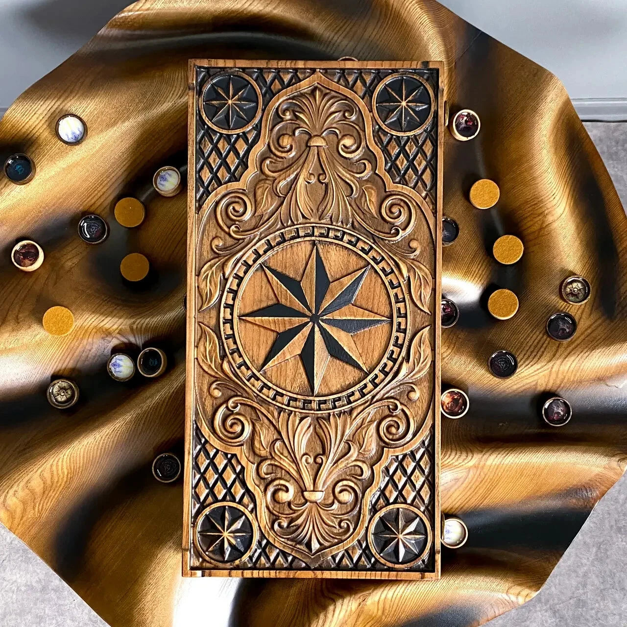 Top view of carved wooden backgammon board with compass rose design surrounded by decorative playing pieces.