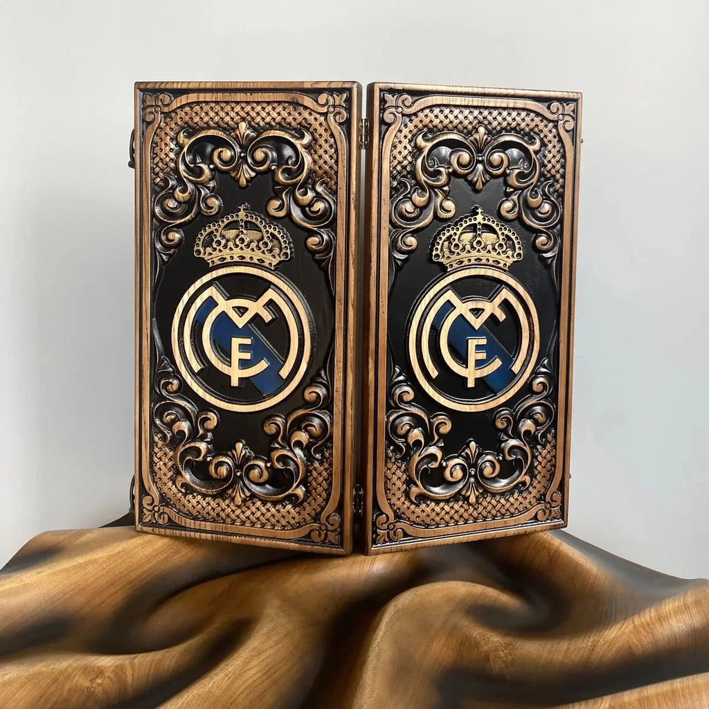 Handcrafted wooden backgammon board with ornate carvings and a gold royal-style emblem on a black background.