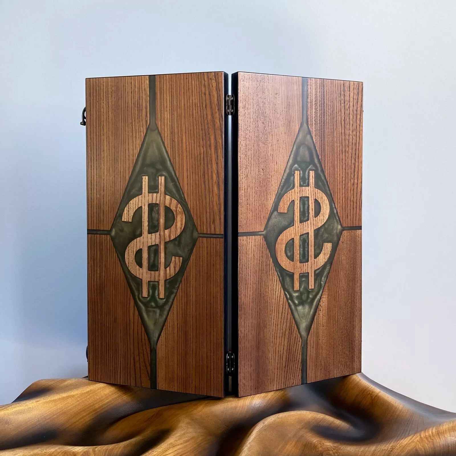 Vertical view of a closed ash wood backgammon board with dual carved dollar symbols and green resin accents.