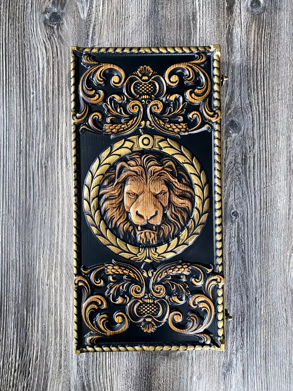 Carved wooden backgammon case with 3D lion head design and ornate decorative patterns, standing upright.