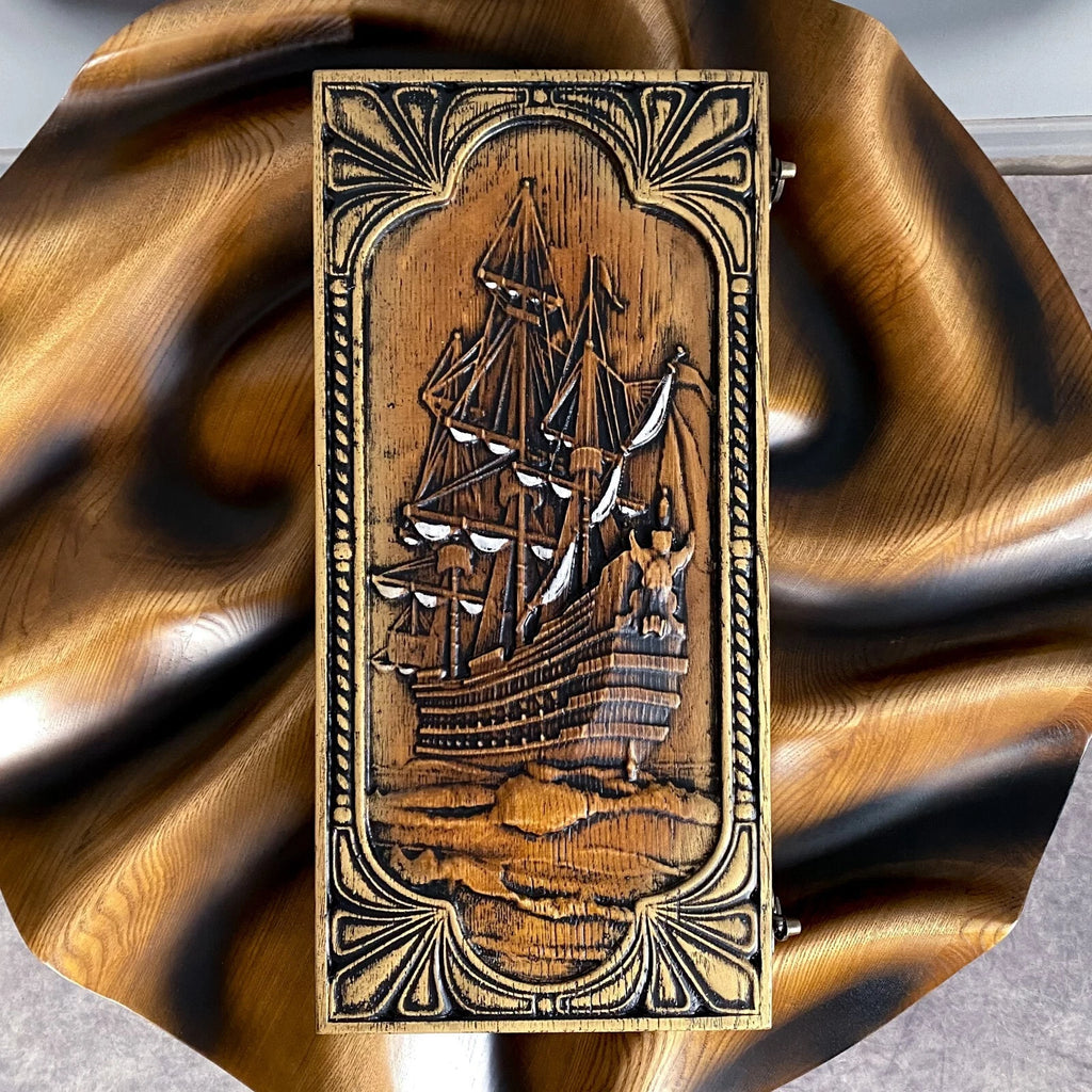 Top view of a carved wooden backgammon board with an intricate sailing ship design on the lid.