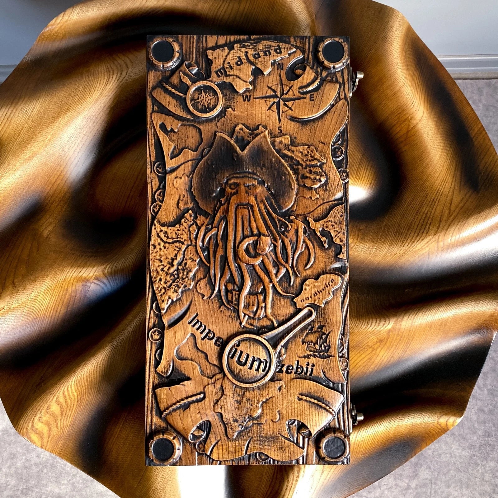 Top view of a carved Davy Jones backgammon board with pirate map, compass, and tentacled face engraving.
