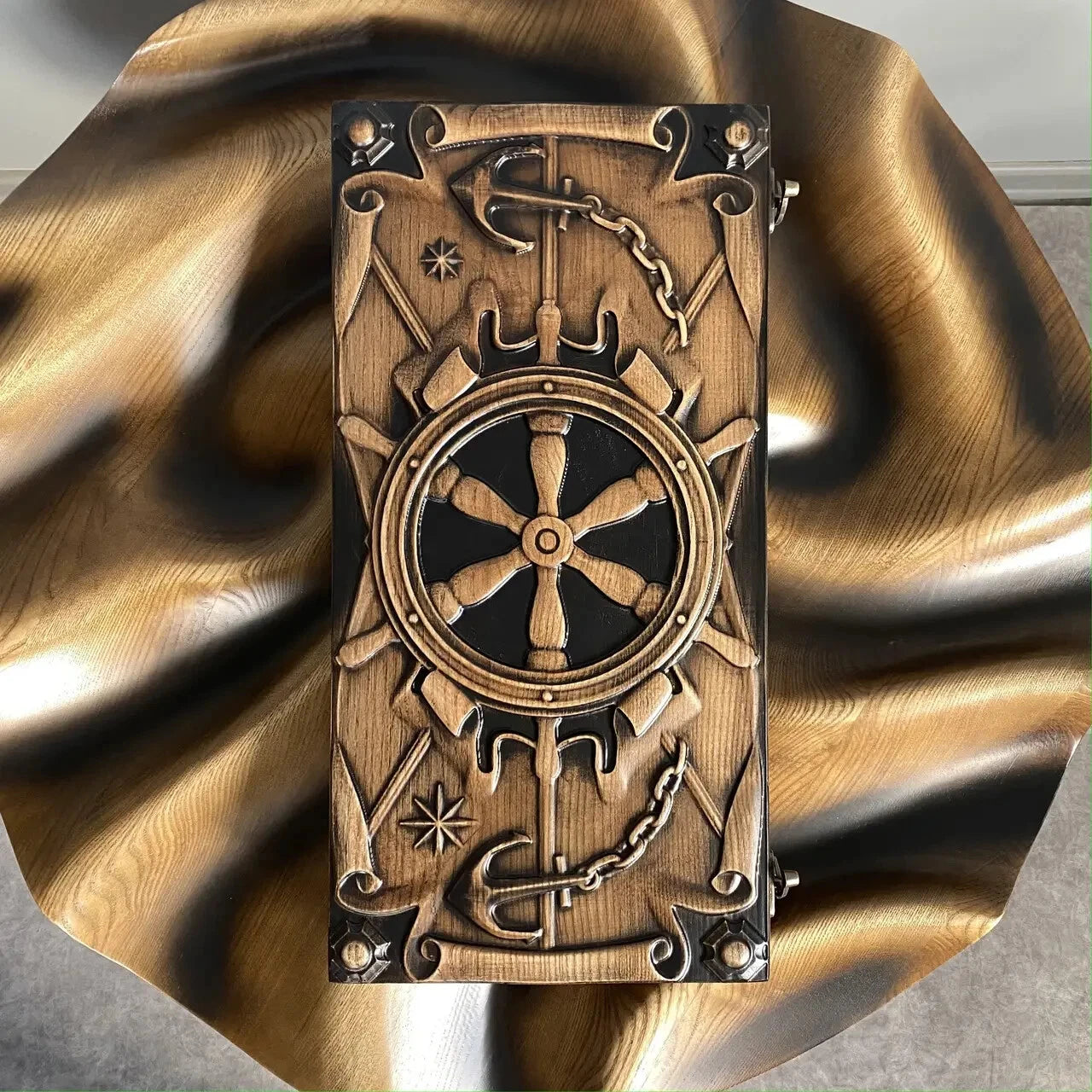 Carved wooden backgammon set with ship wheel and anchor design standing upright on a wooden surface.