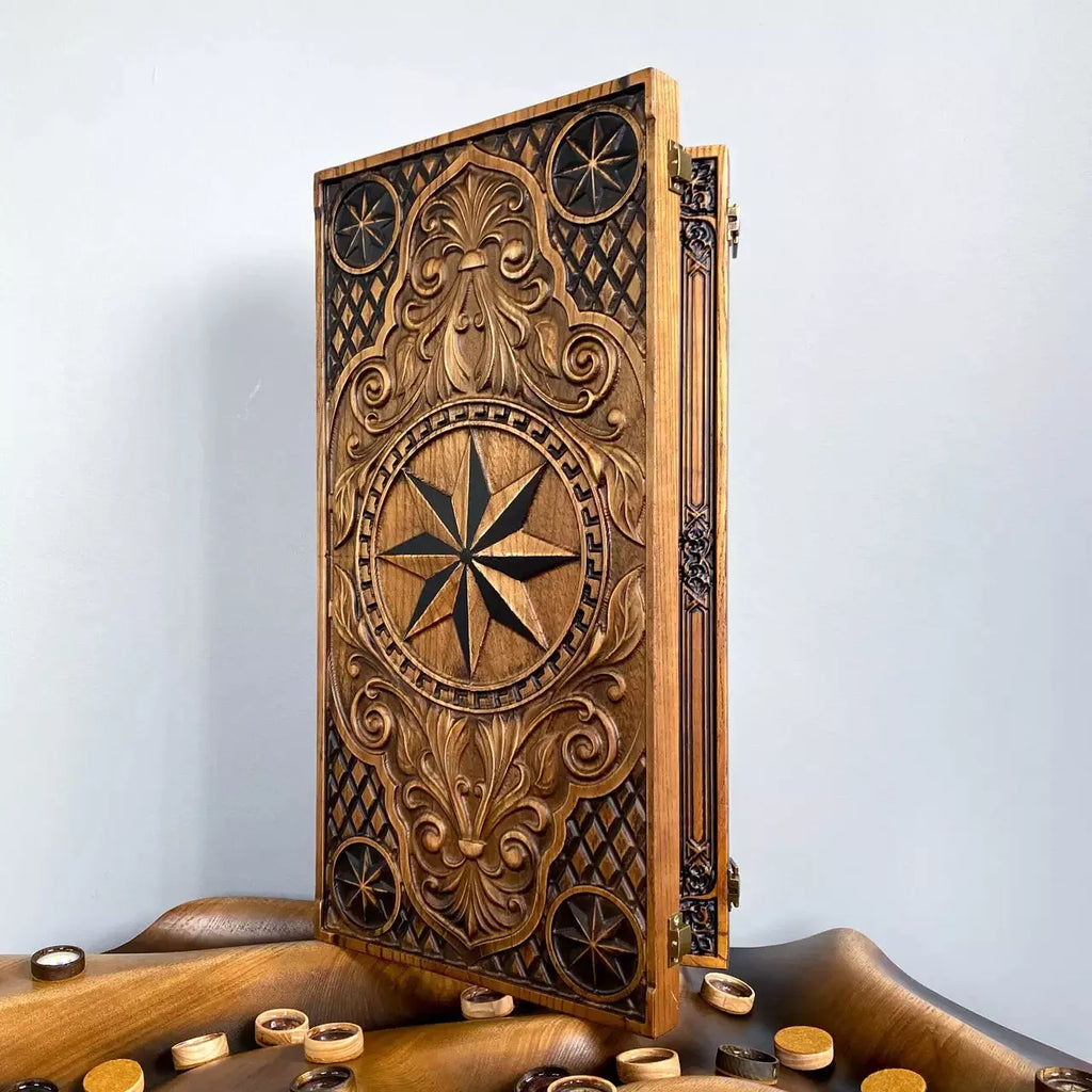 Carved wooden backgammon board with ornate compass and floral motifs standing upright on a wooden surface.