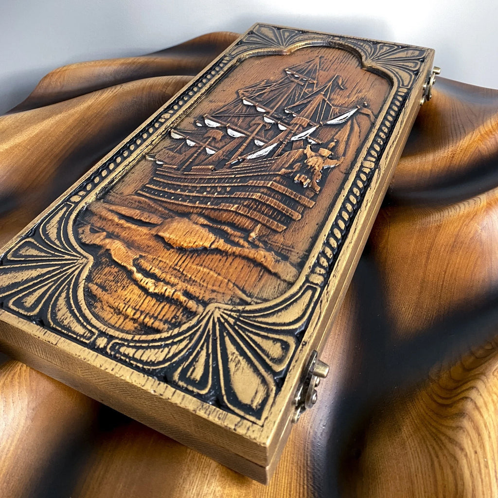 Handcrafted wooden backgammon set photographed from above, showing a detailed ship carving.