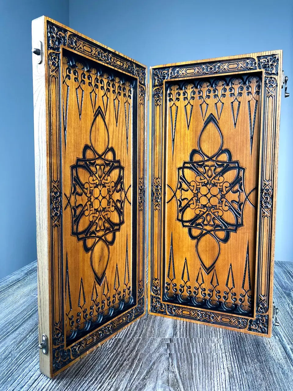 Open wooden backgammon board with detailed oriental carving pattern on ash wood, handcrafted design.