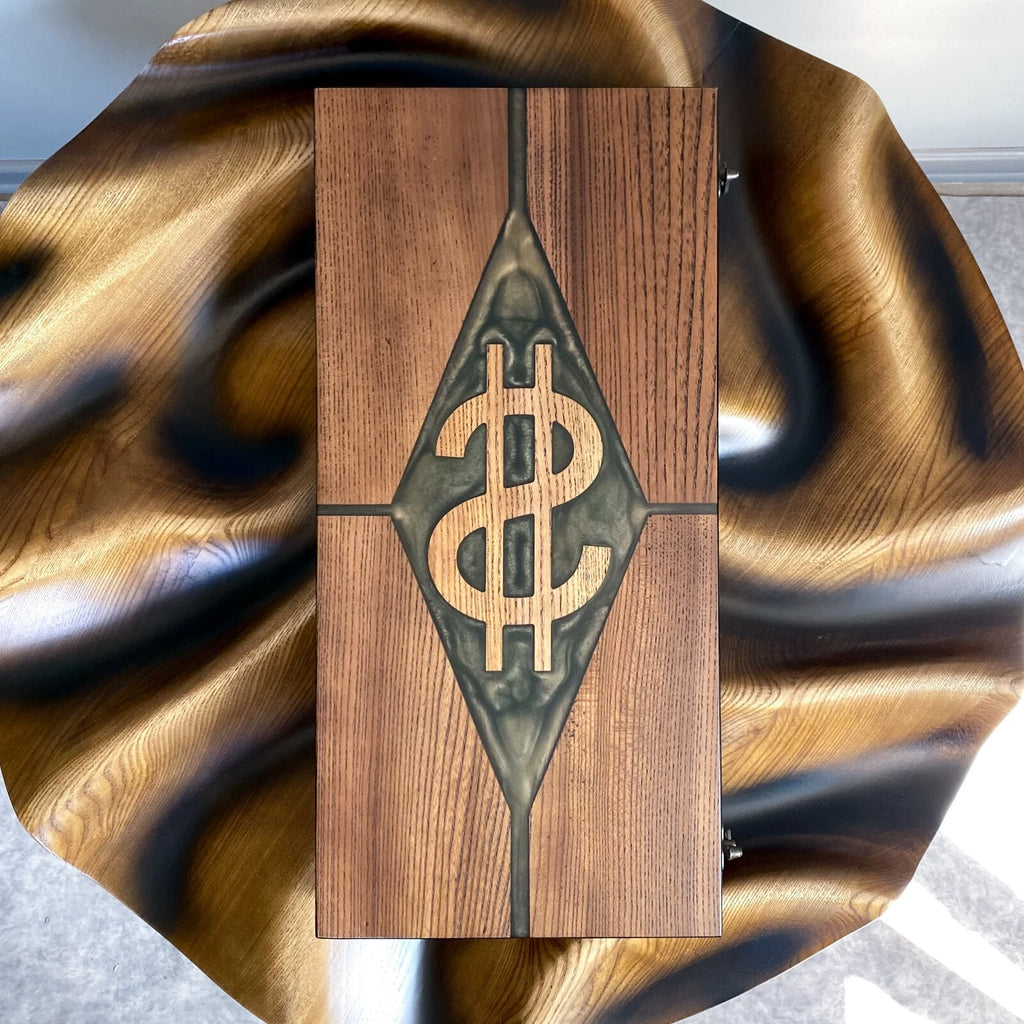 Handmade ash wood backgammon case featuring a dollar sign in a green resin diamond, displayed on a wooden surface.