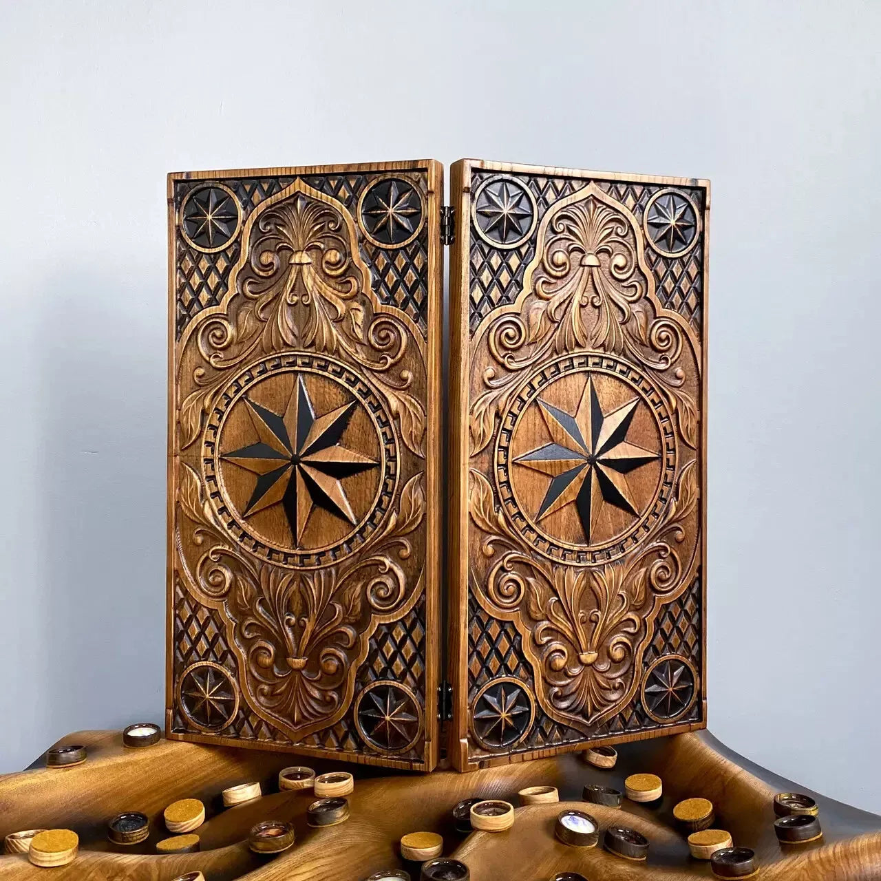 Handcrafted wooden backgammon set with ornate compass rose carving and decorative floral patterns.