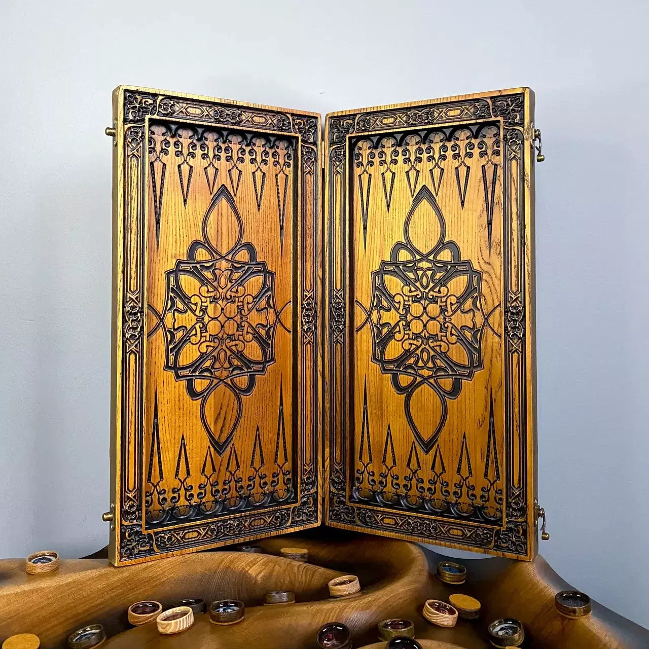 Open wooden backgammon board with intricate oriental-style engravings and decorative patterns.