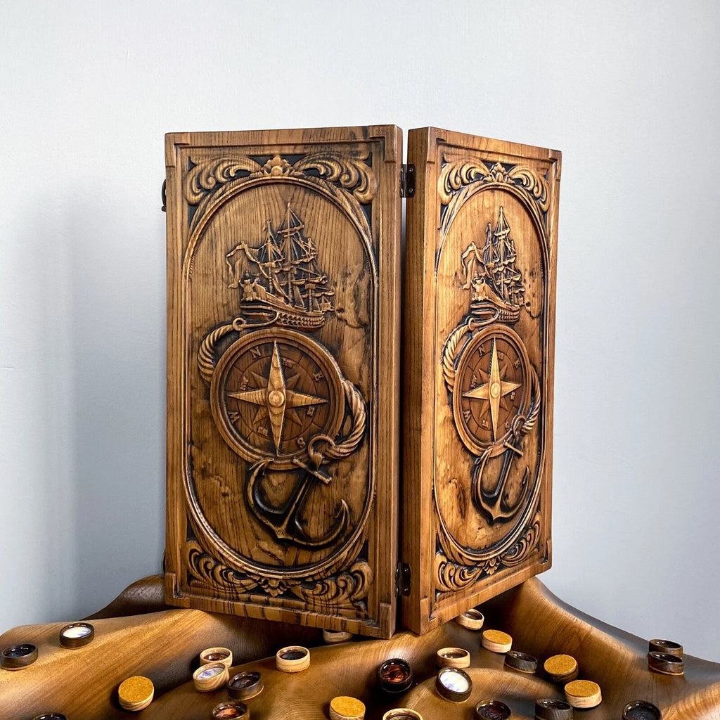 Handmade nautical-style backgammon set showcasing detailed carvings of a ship, compass, and anchor.