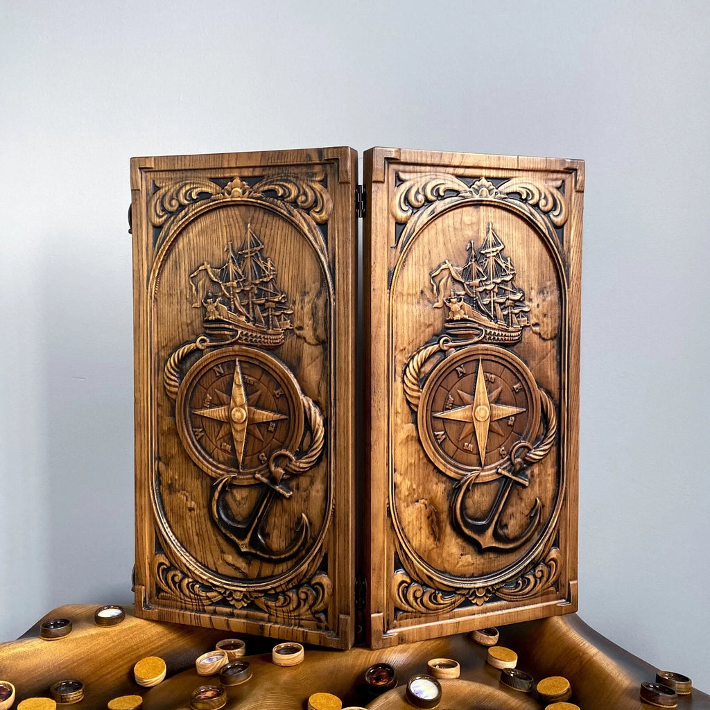 Carved wooden backgammon board with a sailing ship, anchor, and compass design on the front panels.