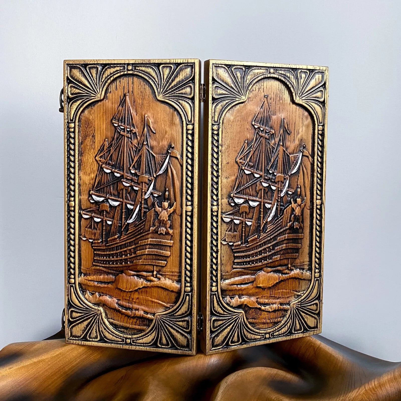 Hand-carved wooden backgammon board with an intricate sailing ship design on the front panel.