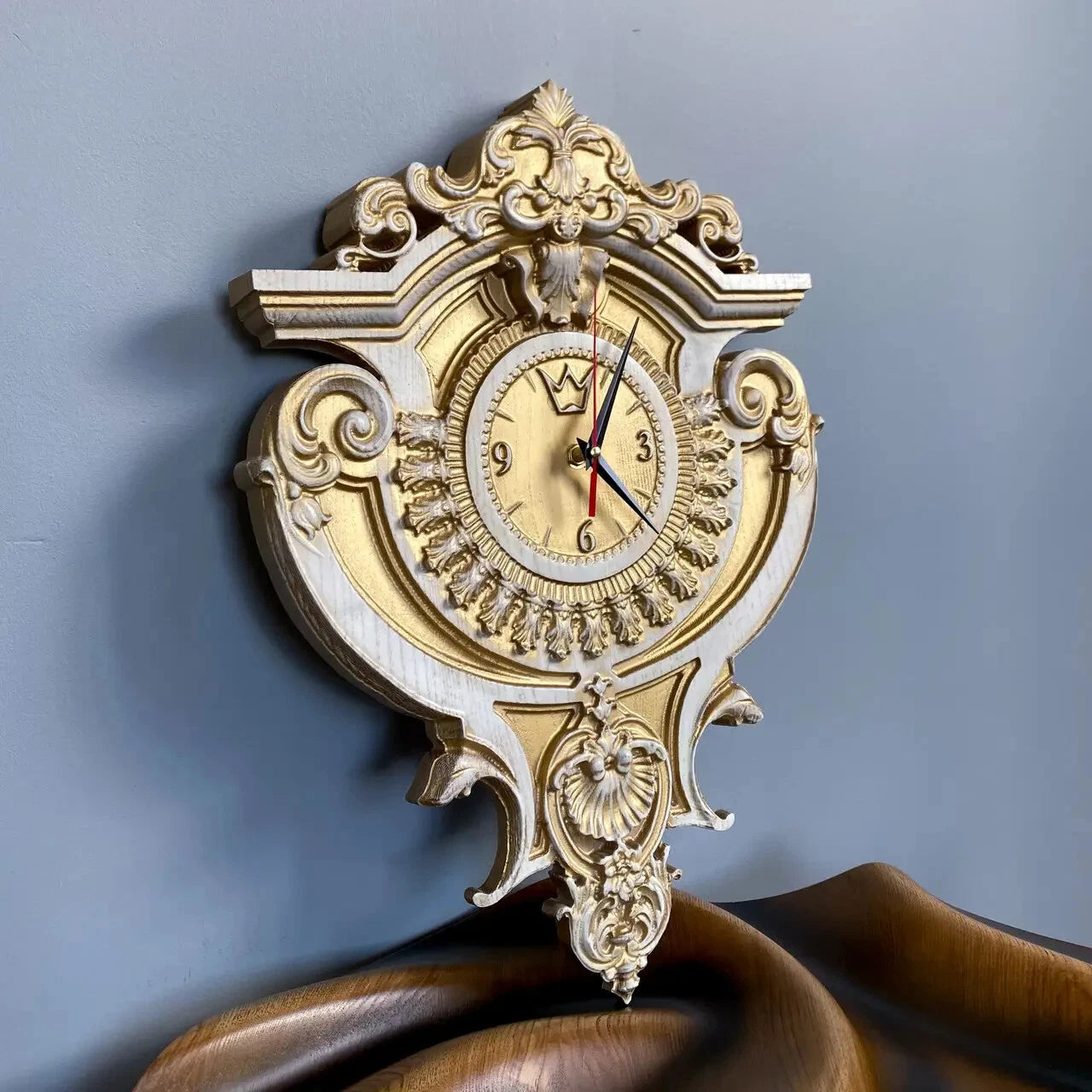Baroque style luxury wall clock made of wood, white and gold carved clock shown at angle on wooden surface